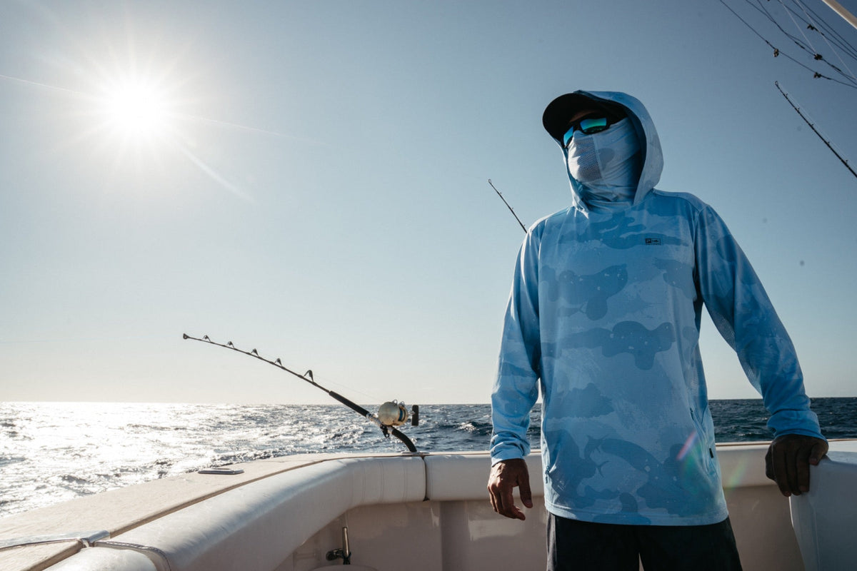 Angler in a hooded Exo-Tech UPF 50+ shirt and face mask beside the rods offshore